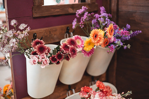 Decorative floral arrangements in white vases on a wooden surface.